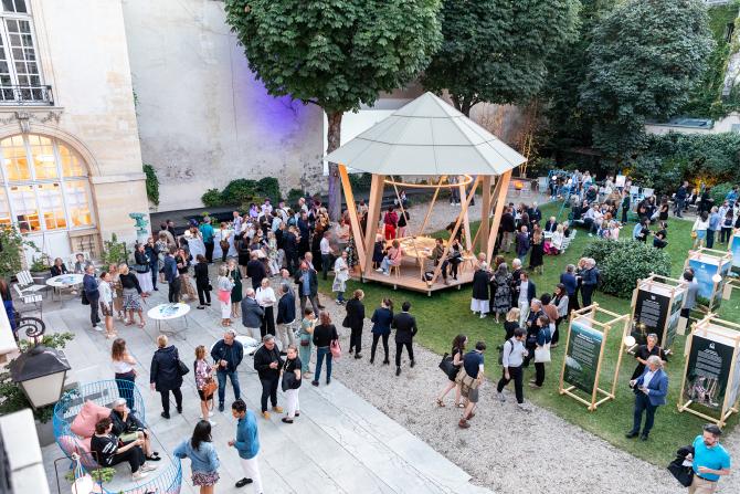 An event with a lot of people in a Parisian garden with a wooden pavilion and the Woodlife Sweden exhibition.