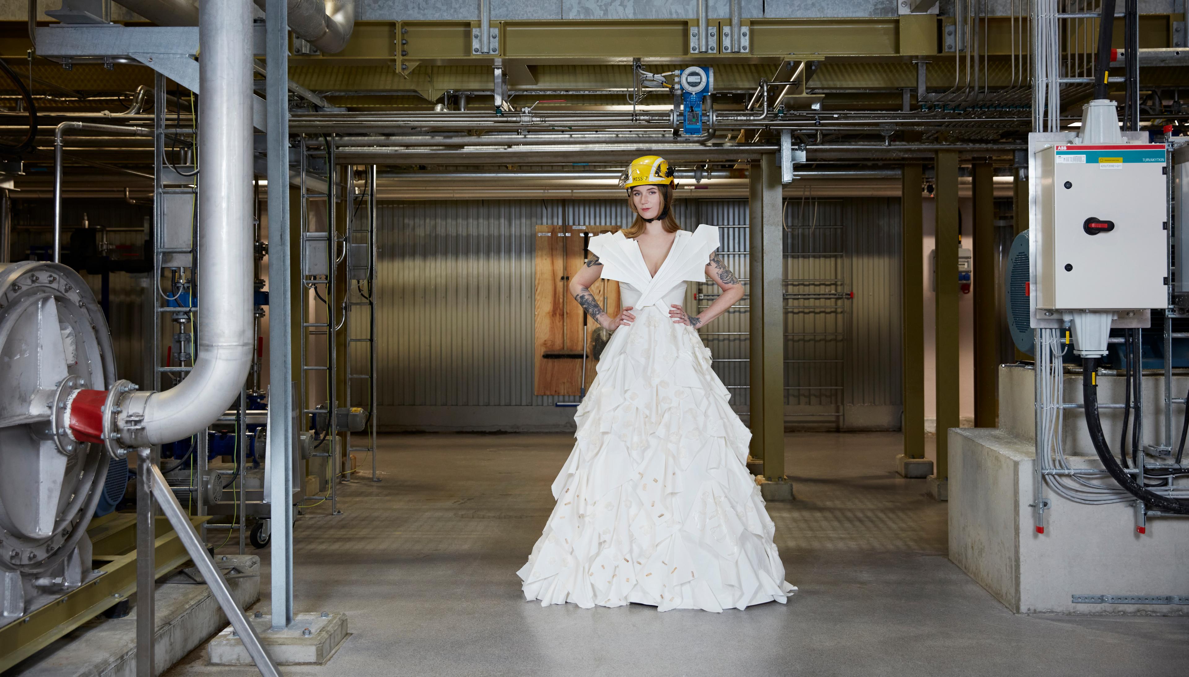 Model in a security helmet wearing a dress made from cellulosic fiber in an industry setting.