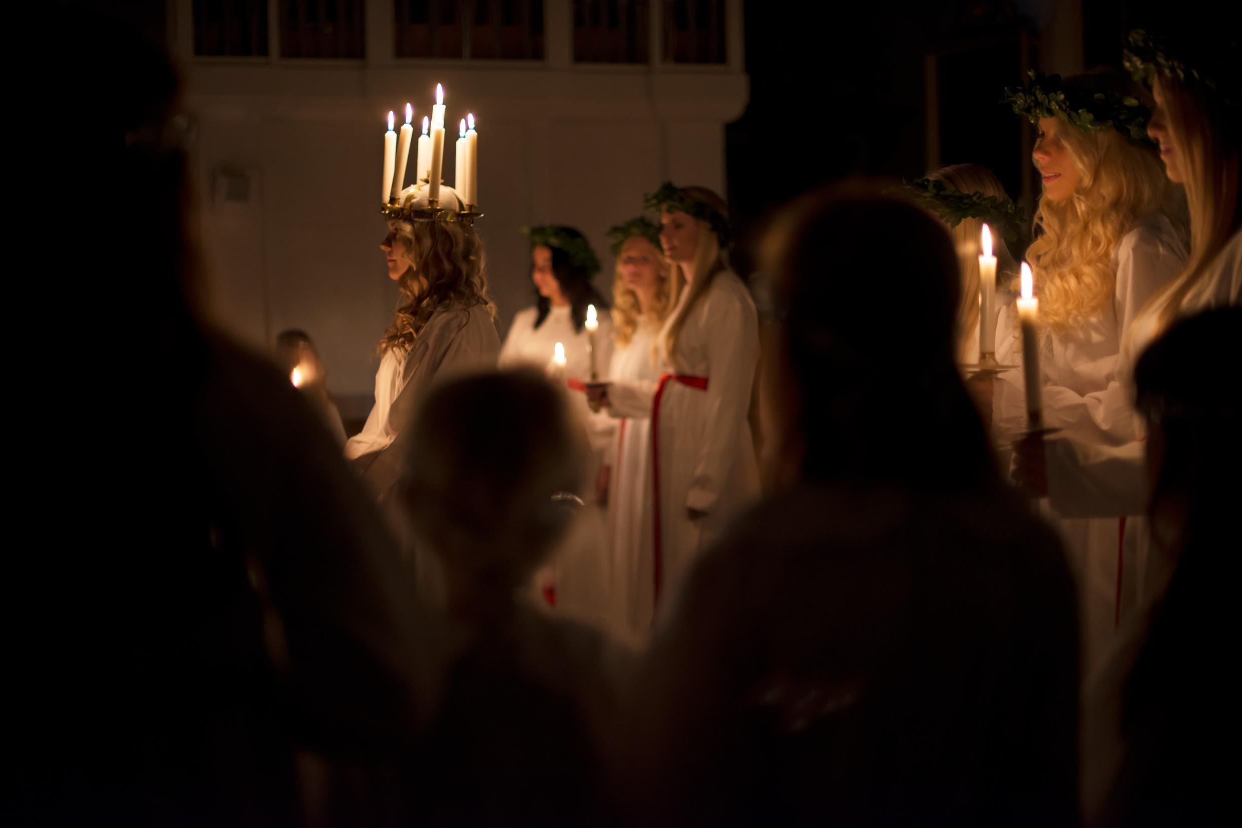 Lucia with her crown of candles and her handmaidens, all dressed in white.