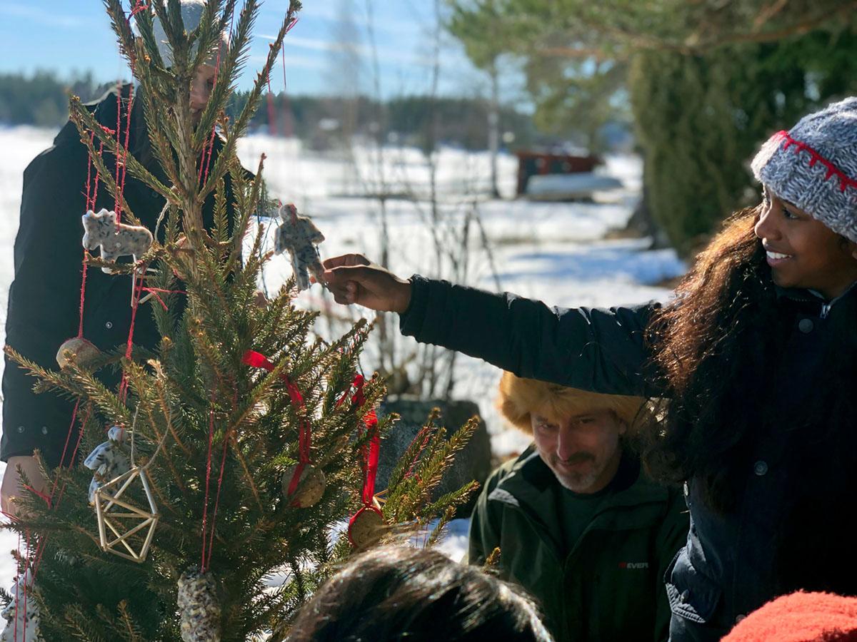 A family decorating a Christmas tree outdoors in winter.