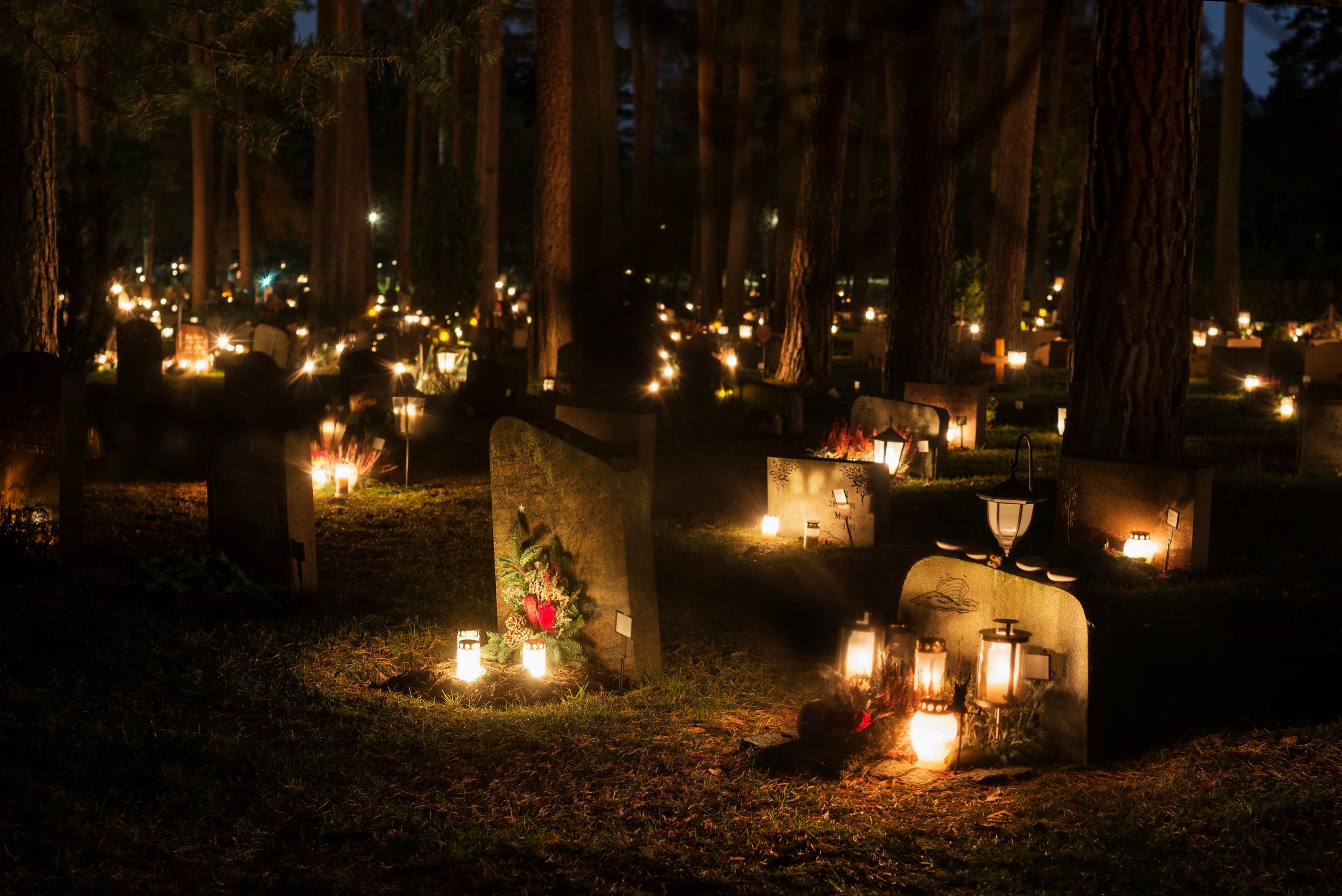 A cemetery with gravestones lit up by candles.