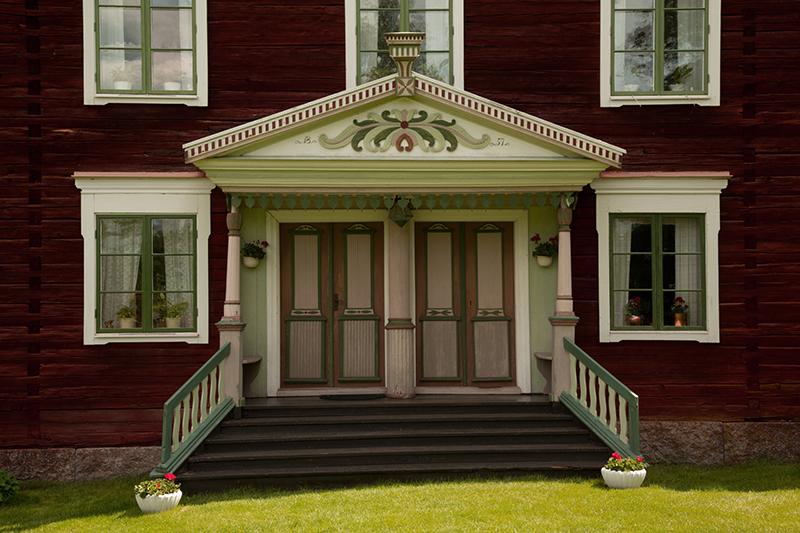 A decorated entrance to a red farmhouse.