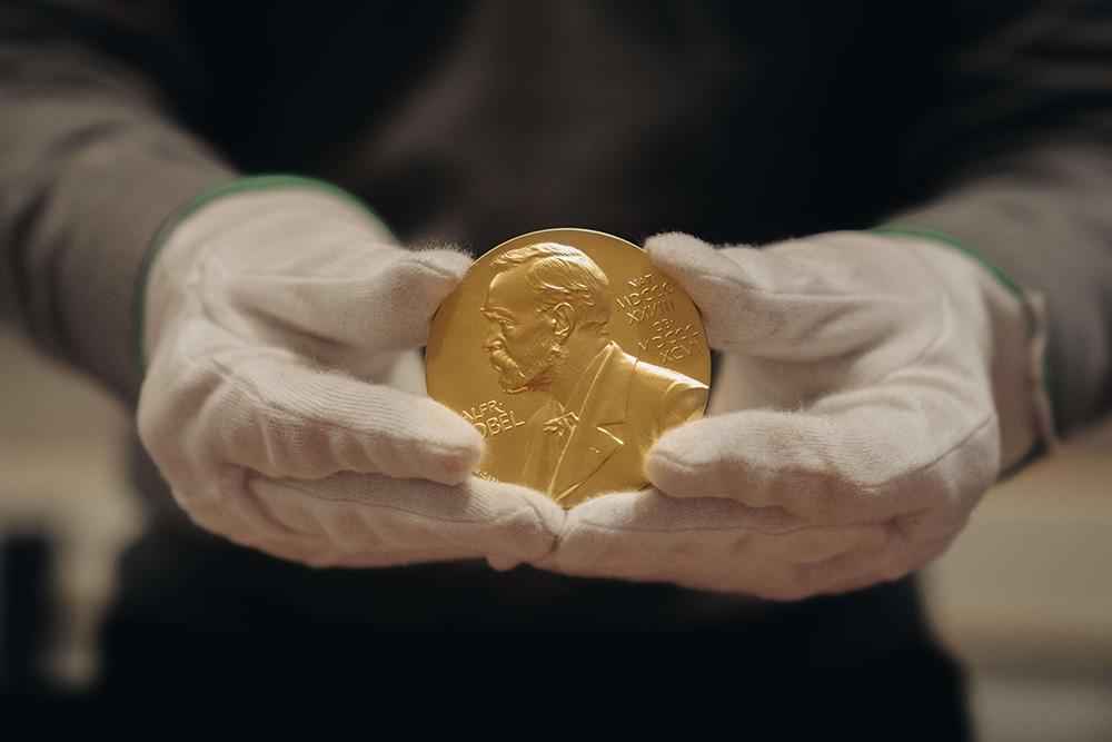 Someone holding the Nobel prize medal.