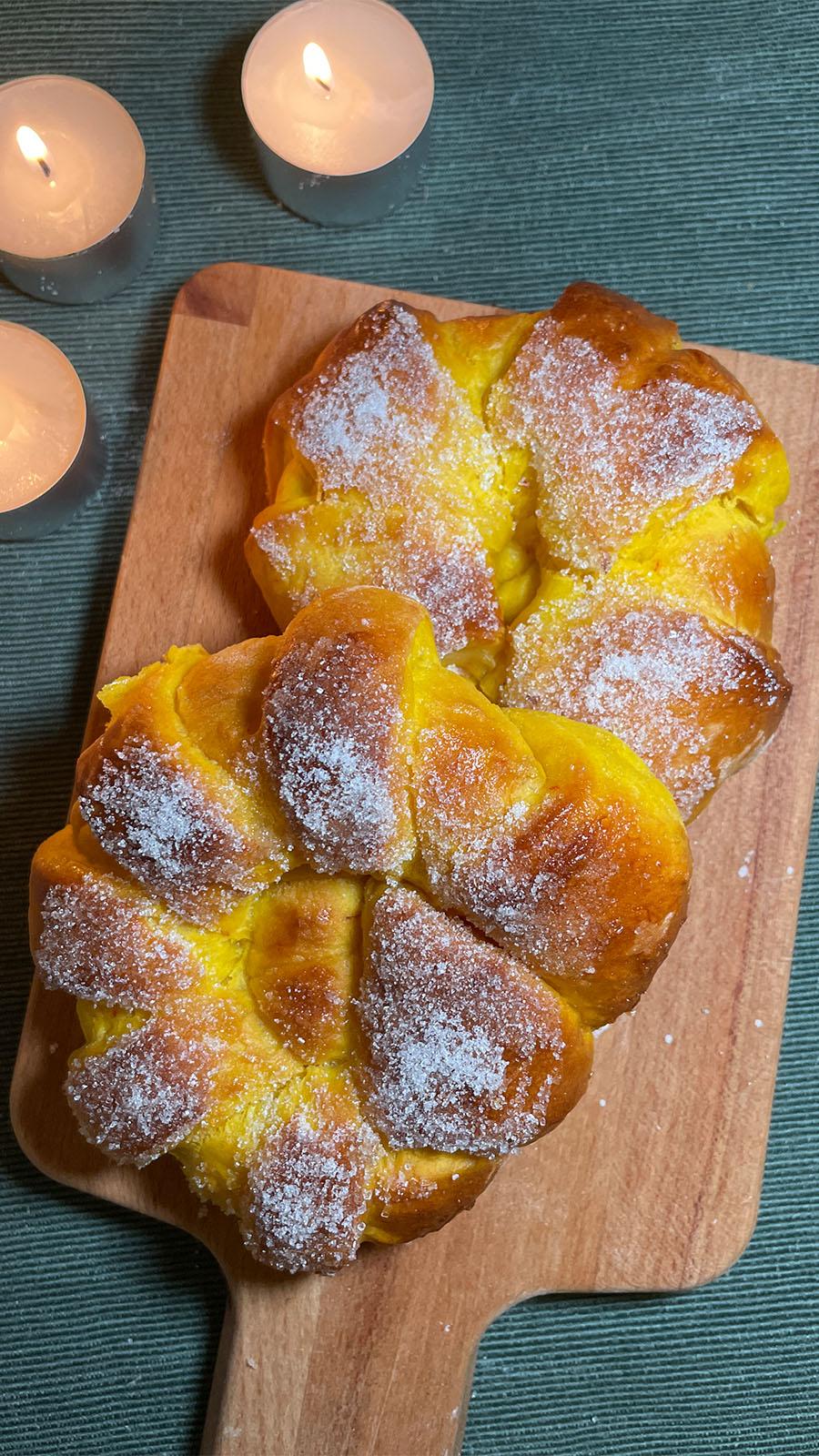 Two saffron buns on a wood tray.