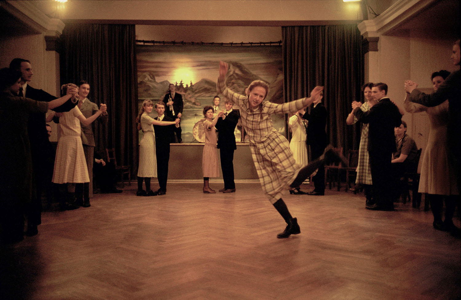 A young Astrid swing dancing while others are dancing formally in couples.